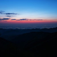 茜色に染まる空と街並みを望む山々のシルエットの写真