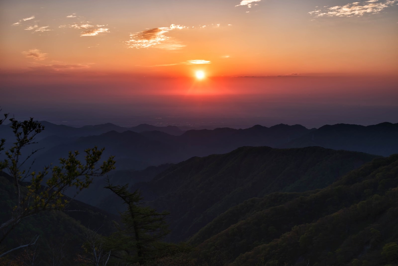 関東平野から昇るオレンジ色の朝日と山並みのシルエット