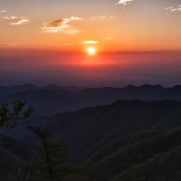 関東平野から昇るオレンジ色の朝日と山並みのシルエットの写真