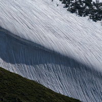 夕暮れの山稜と雪渓模様、遠景の海の写真