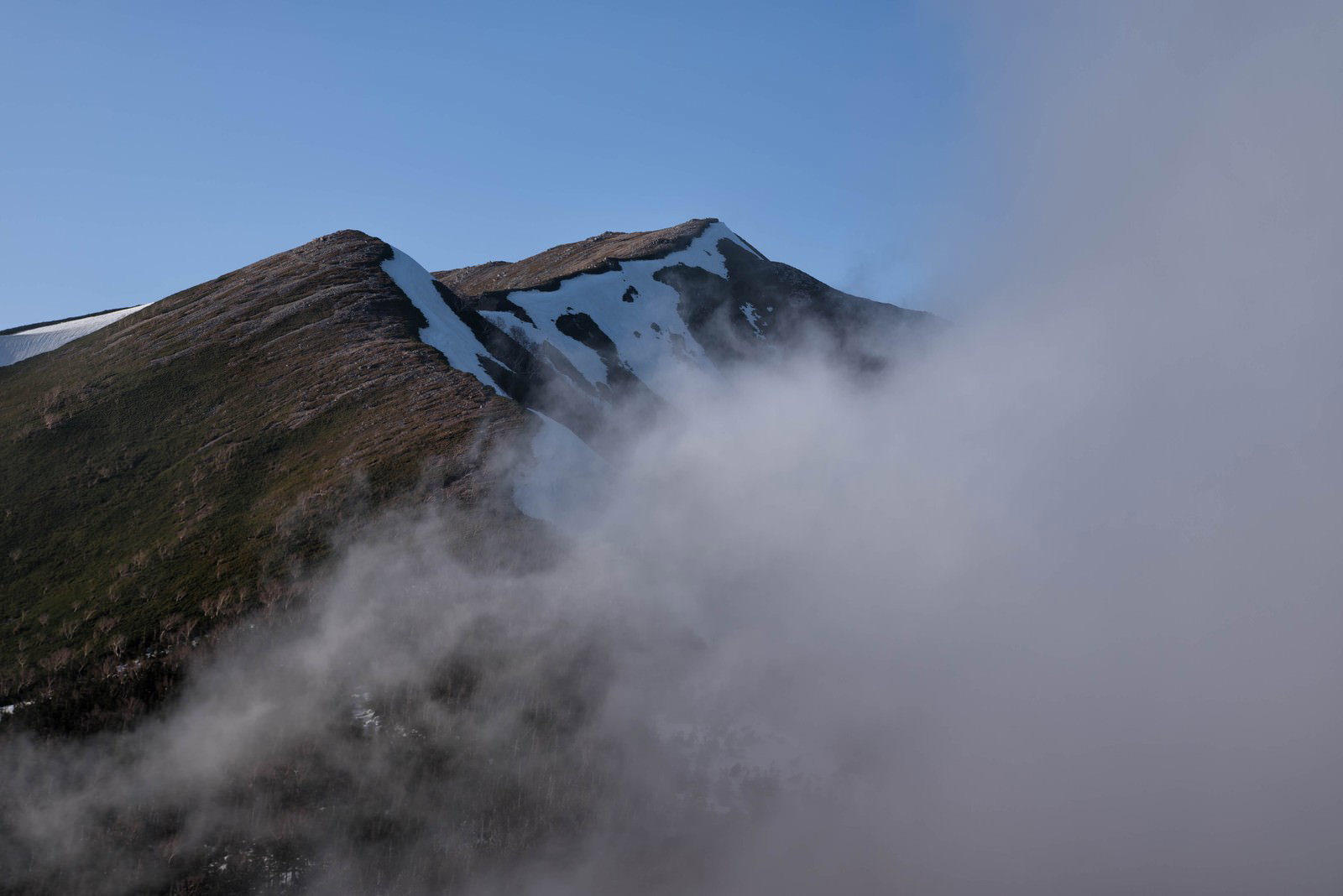 雲やガスに包まれた横通岳の山肌と稜線