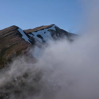 雲に覆われる横通岳の山肌の写真