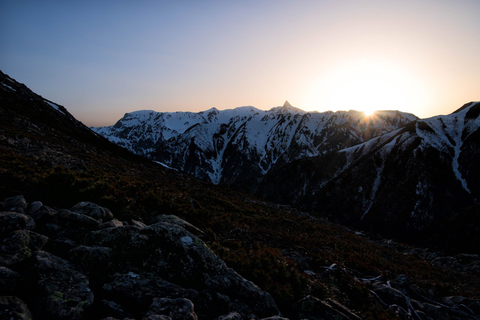飛騨山脈の雪山に沈む夕日と夕焼け空のシルエット