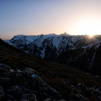 飛騨山脈の雪山に沈み行く太陽の夕焼け風景の写真