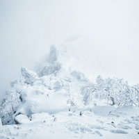 ガスに包まれた稜線と雪景色の冬山岳風景の写真