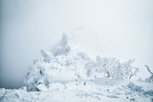 ガスに包まれた稜線と雪景色の冬山岳風景