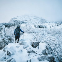 厳冬の登山道で道狭き場所をピッケルを持ちながら歩く登山者の写真