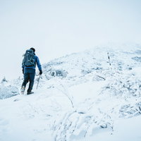ピッケルとアイゼンを装備して雪山に挑む登山者の写真
