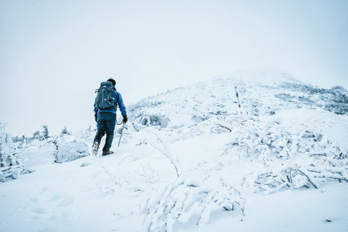 ピッケルとアイゼンを装備して雪山に挑む登山者