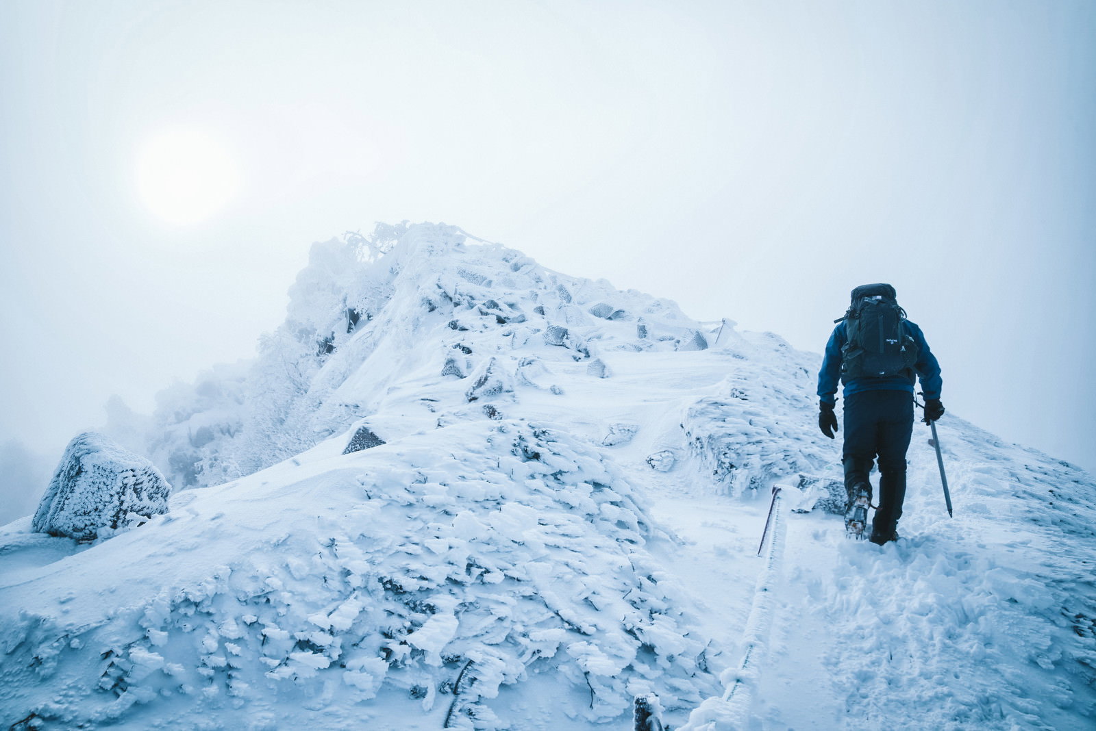 雪に覆われた天狗岳の稜線を歩く登山者の後ろ姿