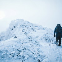 厳冬期の天狗岳の頂上を目指す登山者の後ろ姿の写真