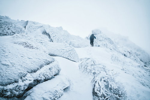 立ち込めるガスの中を登る雪山の登山者の厳冬期登山風景