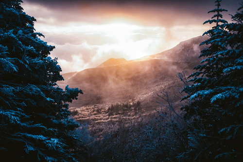 冬の雪山稜線に立つ登山者と夜明けの山並み