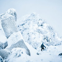 吹雪く天狗岳の稜線で積雪に覆われた冬山を歩く登山者の写真