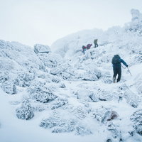 吹雪の悪天候の雪山に挑む登山者達の冬山登山の写真