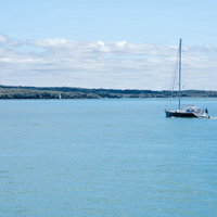 ハウラキ湾に浮かぶ帆を立てていないヨット、ニュージーランドの快晴の海の写真