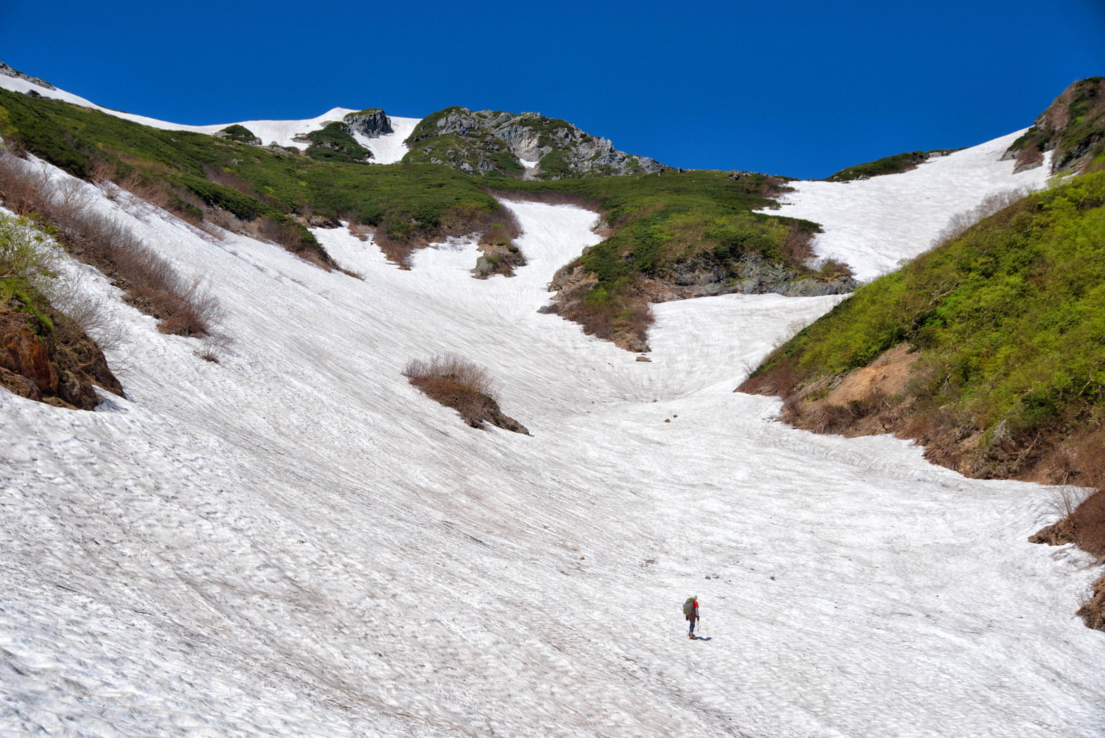 針ノ木岳の白い雪渓を登る登山者の姿と青空