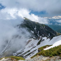 雲かかる新緑の蓮華岳、残雪が残る北アルプスの登山道の写真