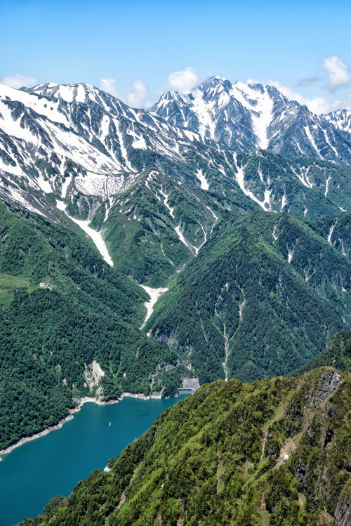 新緑期の黒部ダムと残雪の剱岳、北アルプスの山脈