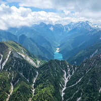 残雪と新緑が彩る北アルプス深部の山脈景観の写真