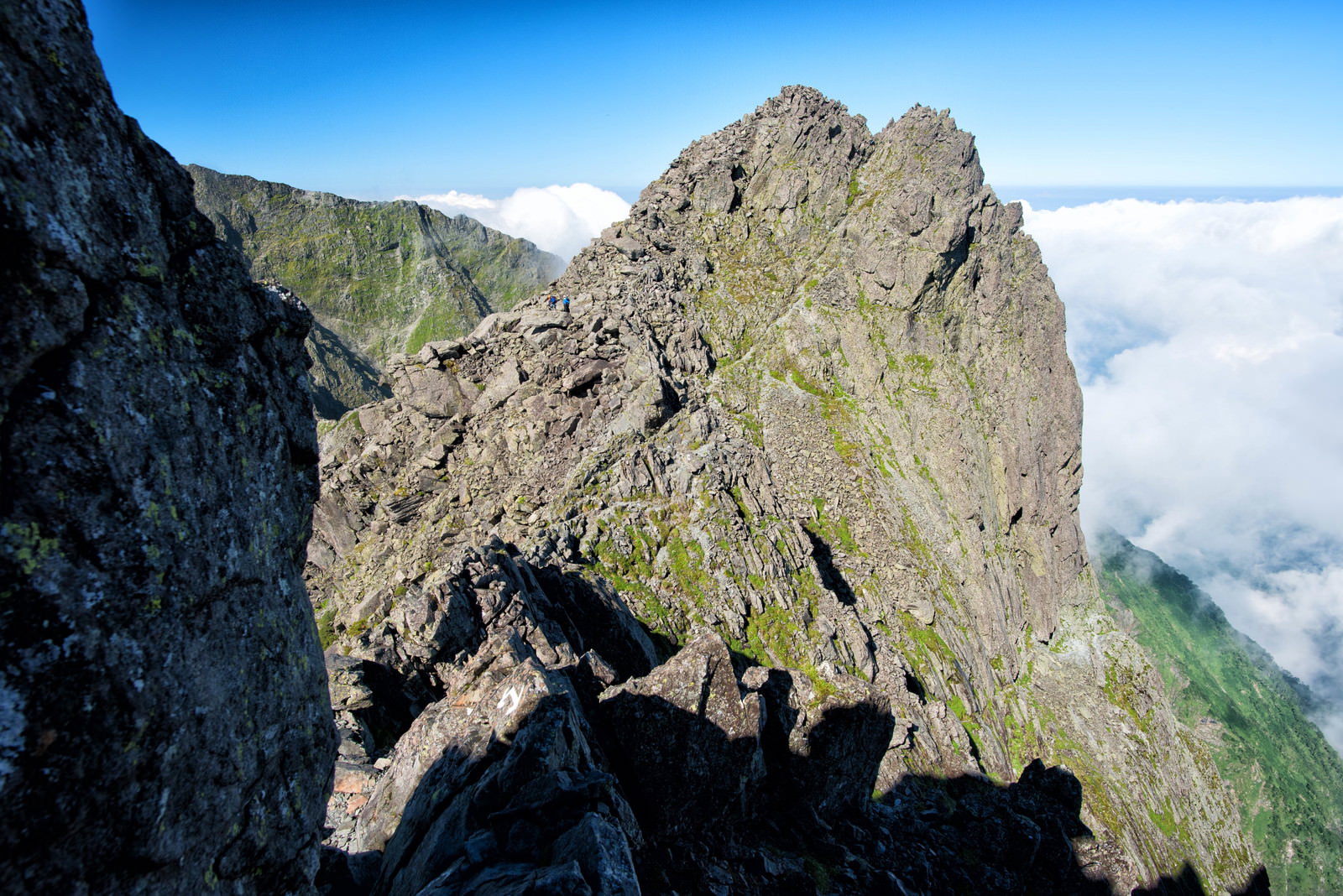 北穂高岳山頂下の岩稜帯で岩場を登る登山者と雲海の風景