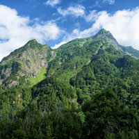 夏季の新緑に包まれた明神岳の登山風景と青空の写真
