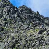 涸沢槍直下の険しい岩稜鎖場を登る登山者たちの写真