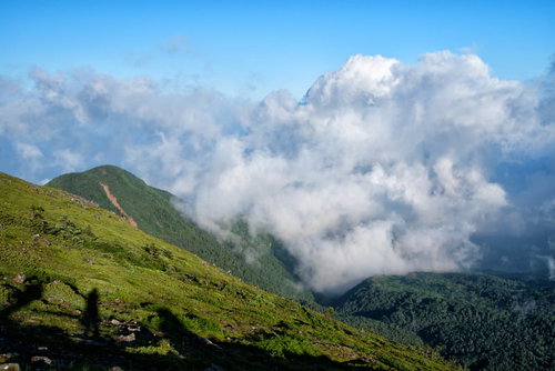 湧き上がってくる積雲と登山道に映る登山者の影
