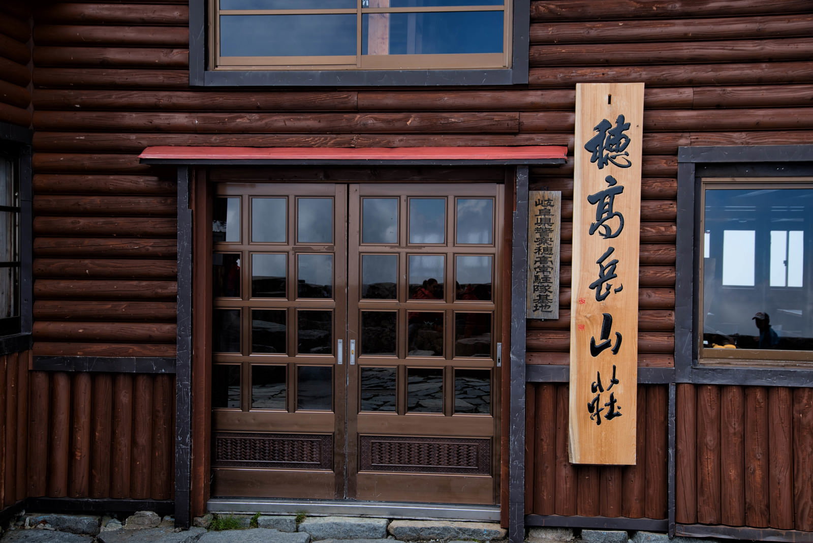 木造の山小屋の玄関前に設置された達筆な縦書き看板