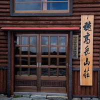 穂高岳山荘の玄関に掲げられた達筆な看板と木造建築の写真