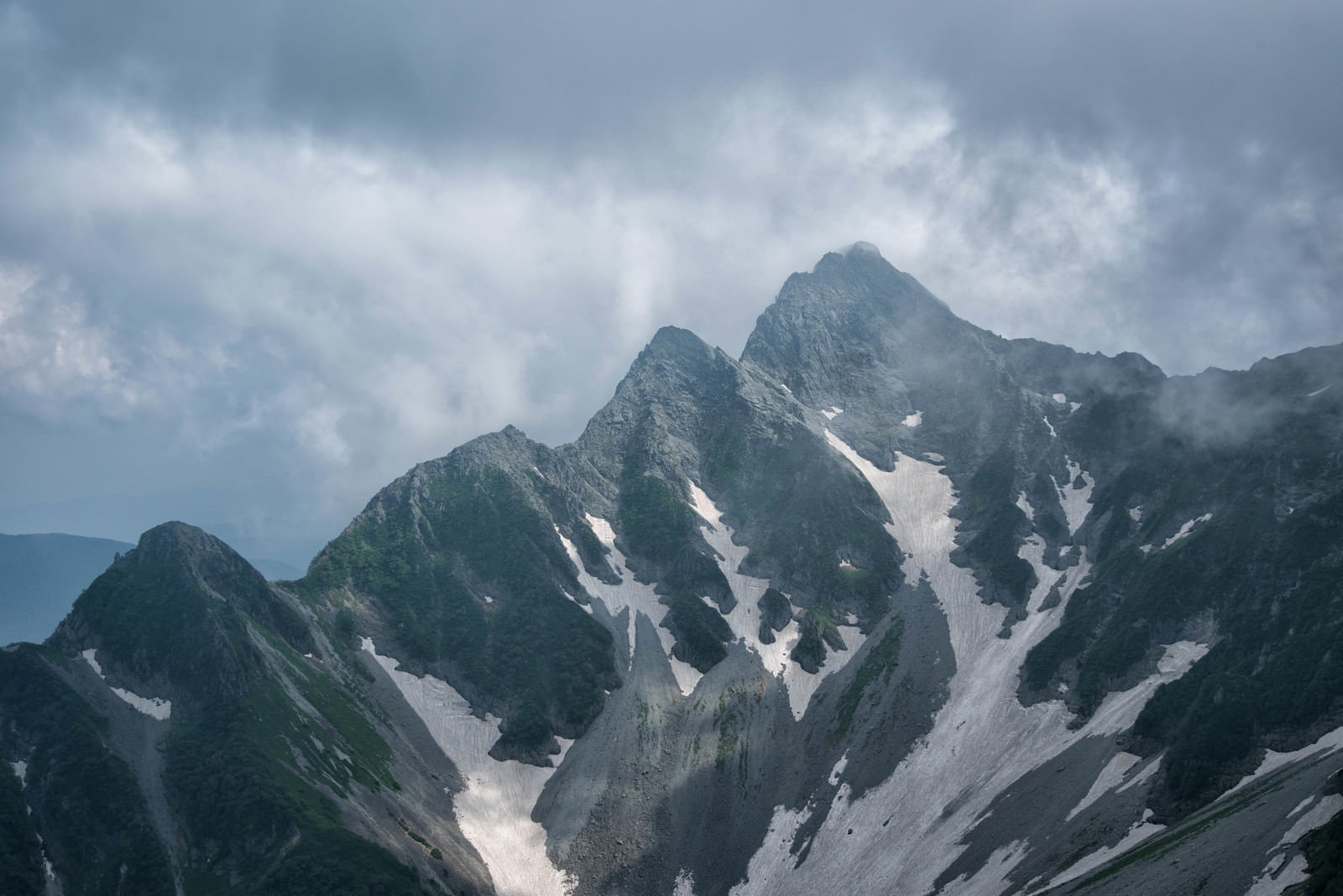 雲間から差し込む光に照らされた前穂高岳北尾根の山景色