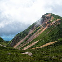 曇り空の中、登山道から見た西天狗岳（八ヶ岳連峰）の写真