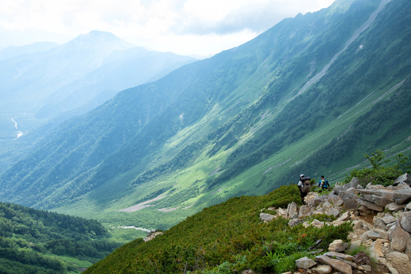 霧がかかる山道を歩く登山者