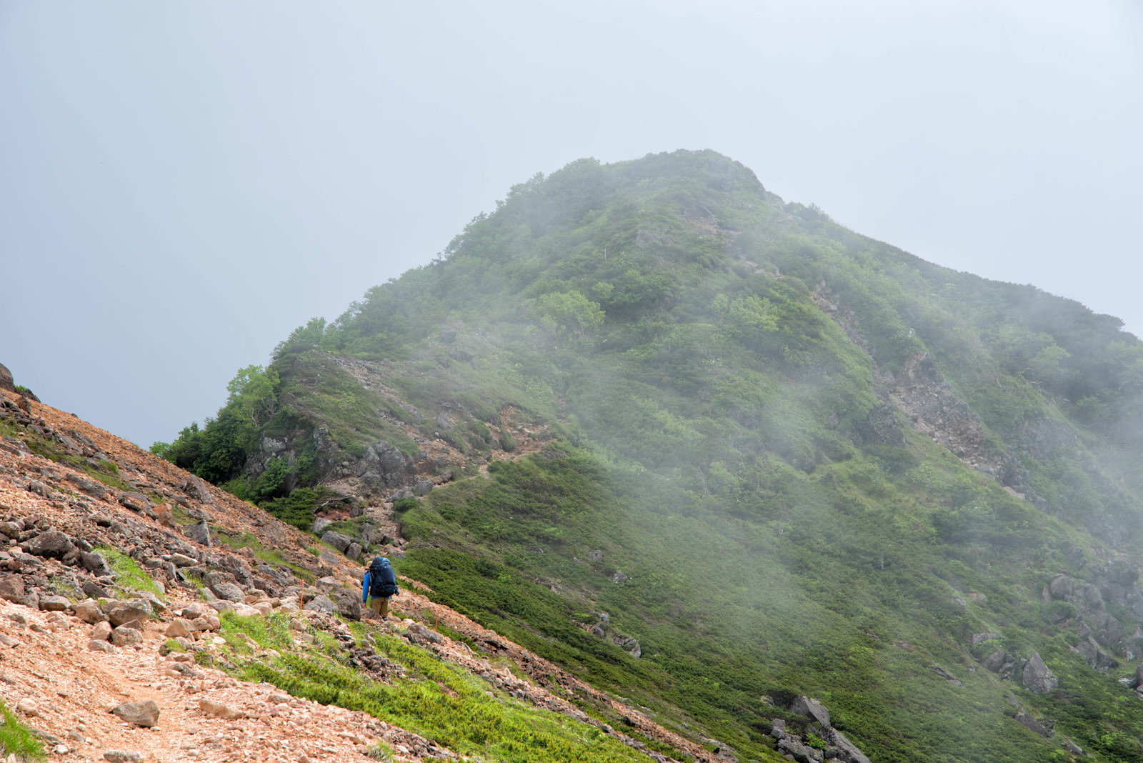 霧に包まれた山の稜線を歩く登山者の後ろ姿