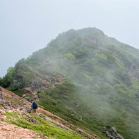 雲に覆われた稜線を歩く登山者の登山道での登山風景の写真