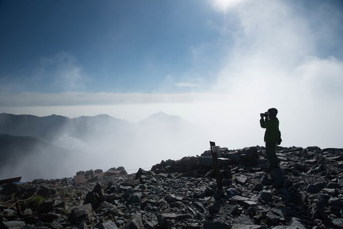 雲の上の北穂高岳山頂に立つ登山者（北アルプス）