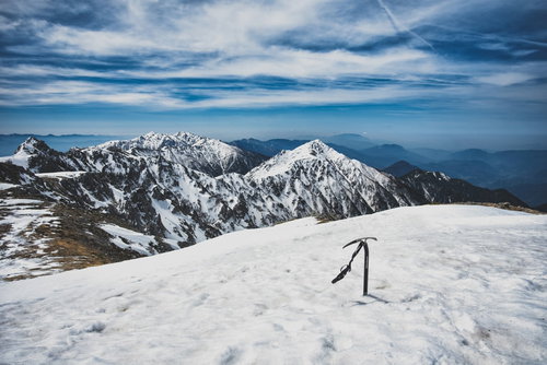 中央アルプスの雪に突き立てられたピッケルと冬の稜線