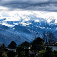 雲間から姿を現す後立山連峰の飛騨山脈、北アルプスの雪を頂いた峰々の写真