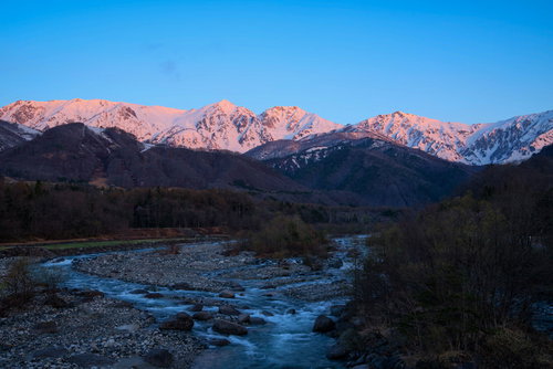 朝焼けに染まる白馬三山と霧の渓流