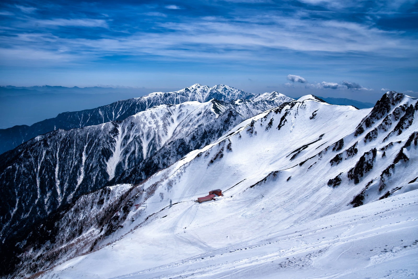 残雪と岩が続く高山の稜線と遠景の山脈