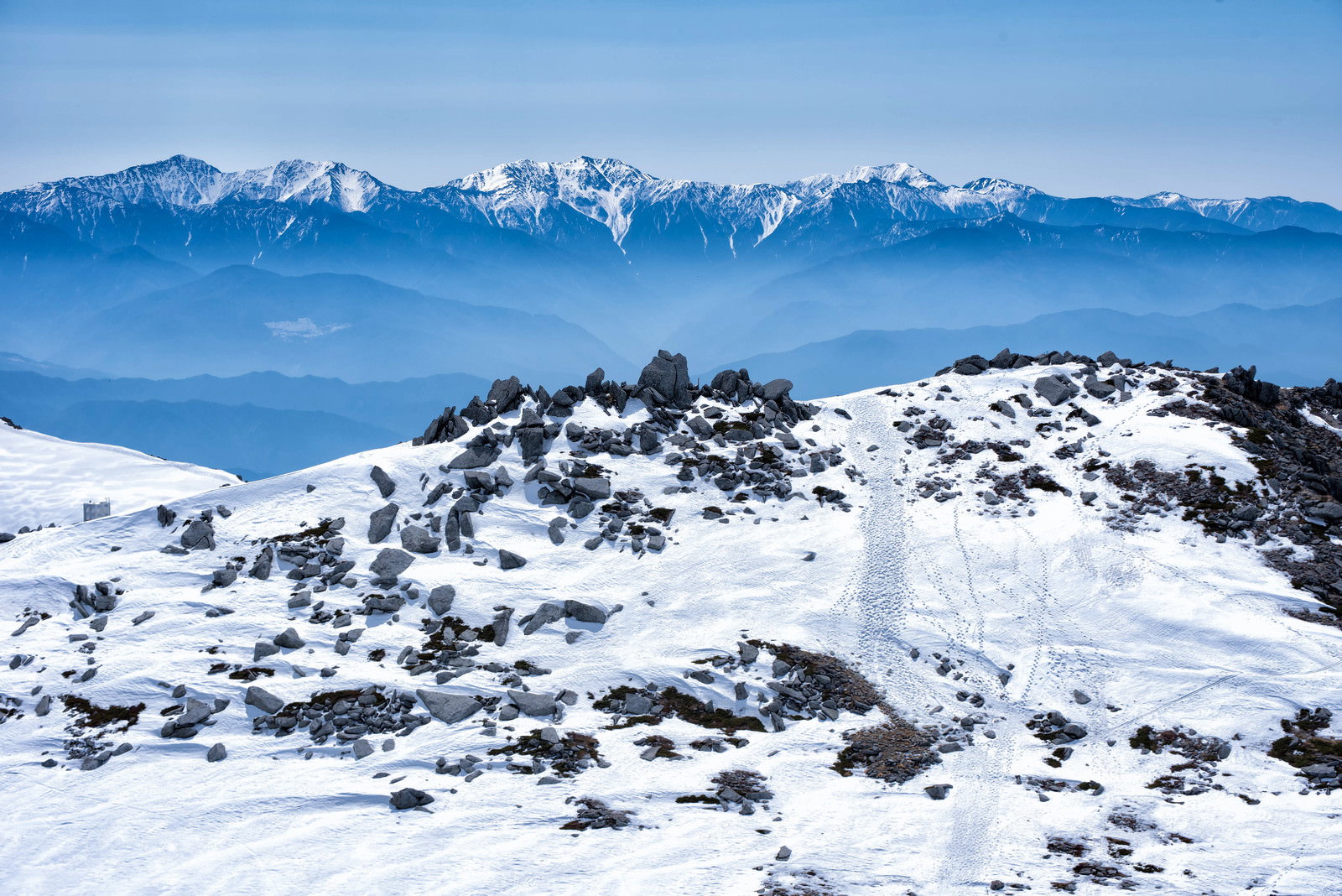 雪残る中岳のガレ場と遠くに見える雪化粧した南アルプスの山々