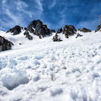 中央アルプスの雪崩跡に鋭く突き出す黒い岩肌の写真