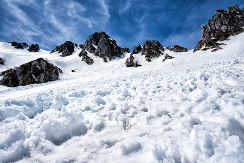 中央アルプスの雪崩跡に鋭く突き出す黒い岩肌
