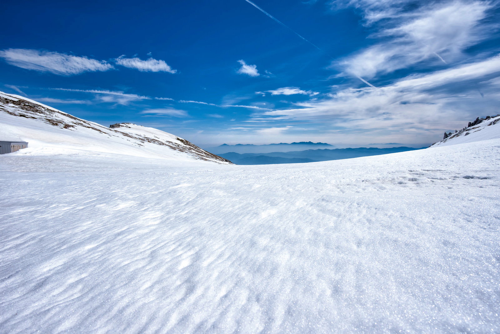 真っ白な雪原の向こうに八ヶ岳の雪化粧した山々が見える冬の風景