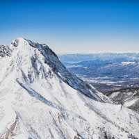 雪に覆われた阿弥陀岳と北アルプスの連峰の写真