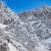 冬の登山道で雪と氷に覆われた岩壁に挑む登山者の写真