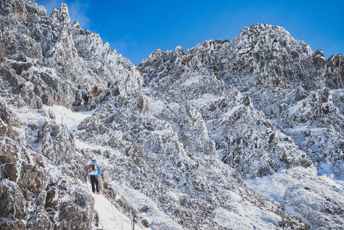 冬の登山道で雪と氷に覆われた岩壁に挑む登山者