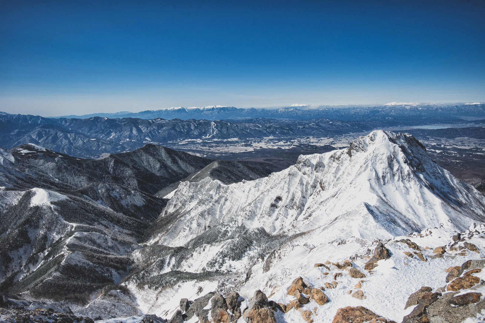 雪に覆われた八ヶ岳連峰の山々を赤岳山頂から見下ろした冬の景色