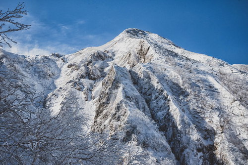 北アルプス中岳北面の岩壁に伸びる影と雪景色