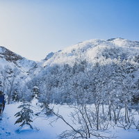 文三郎尾根の登山道の始まりで雪道を進む登山者の写真